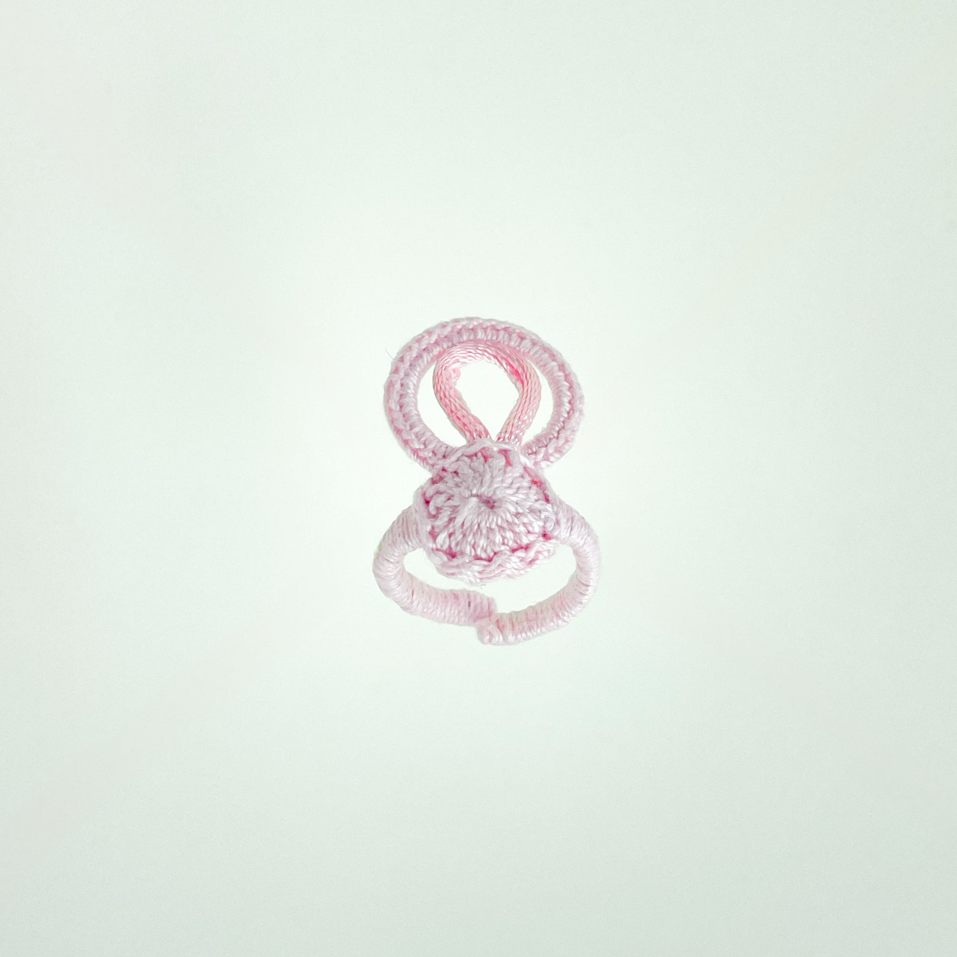 Blossom collection crochet ring in rose, photographed at a 45-degree angle to emphasize its soft curves and artisanal detail.