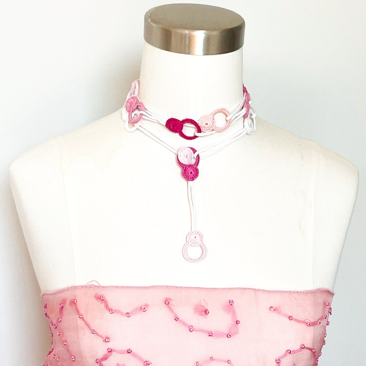 Rose adjustable crochet necklace on mannequin worn as a choker, soft cotton thread wrapped close to the neck with end draping forward