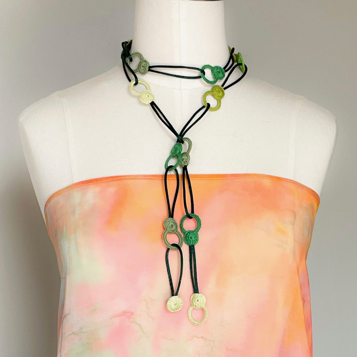 Green looped crochet necklace on mannequin styled as a lariat with loose knot and long drop effect, artisan made in Chicago
