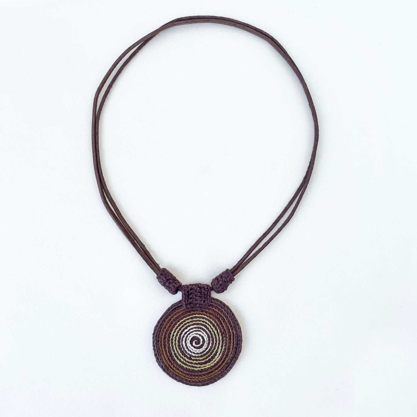 Necklace with a spiral pendant in brown and green tones with vegan suede adjustable straps on a white background.