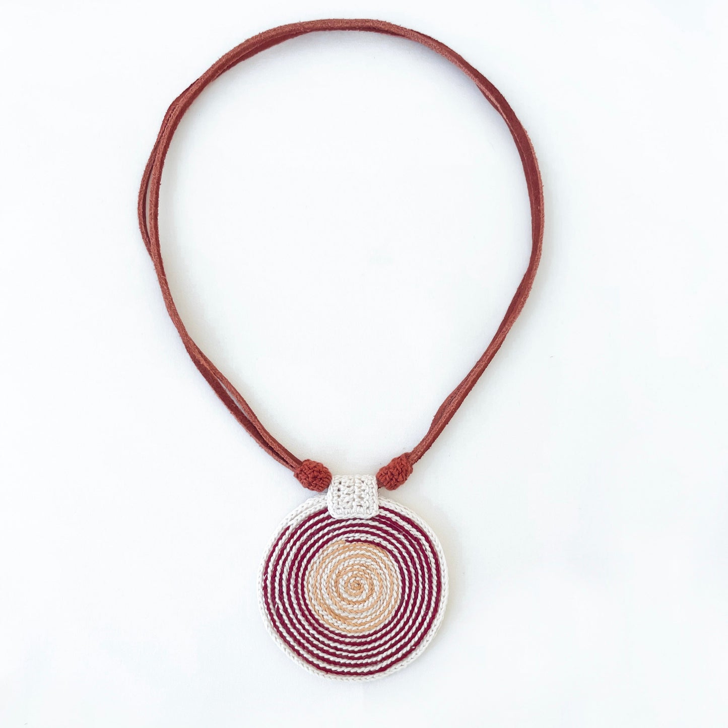 Necklace with a spiral pendant in burgundy, Ivory and gold with vegan suede adjustable straps on a white background.