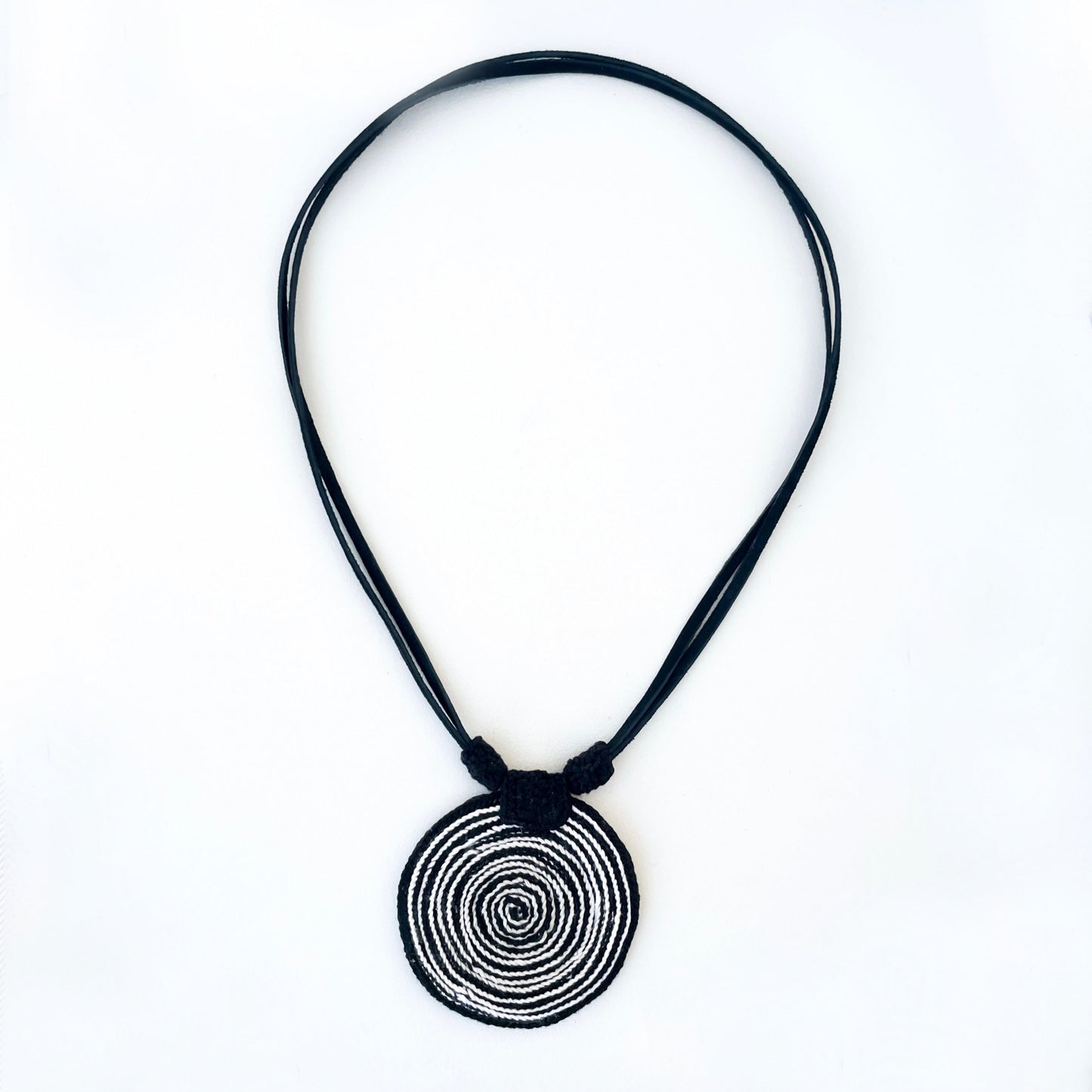 Necklace with a spiral pendant in black and white with vegan suede adjustable straps on a white background.