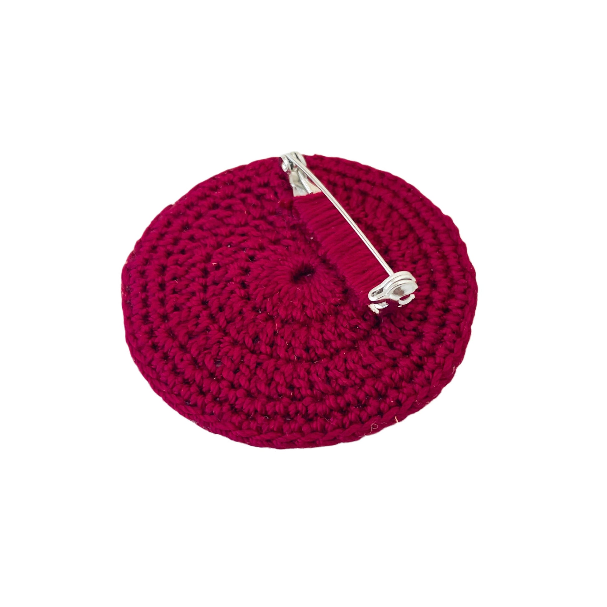 Back view of crochet Spiralis Pin with clasp on burgundy crochet circle
