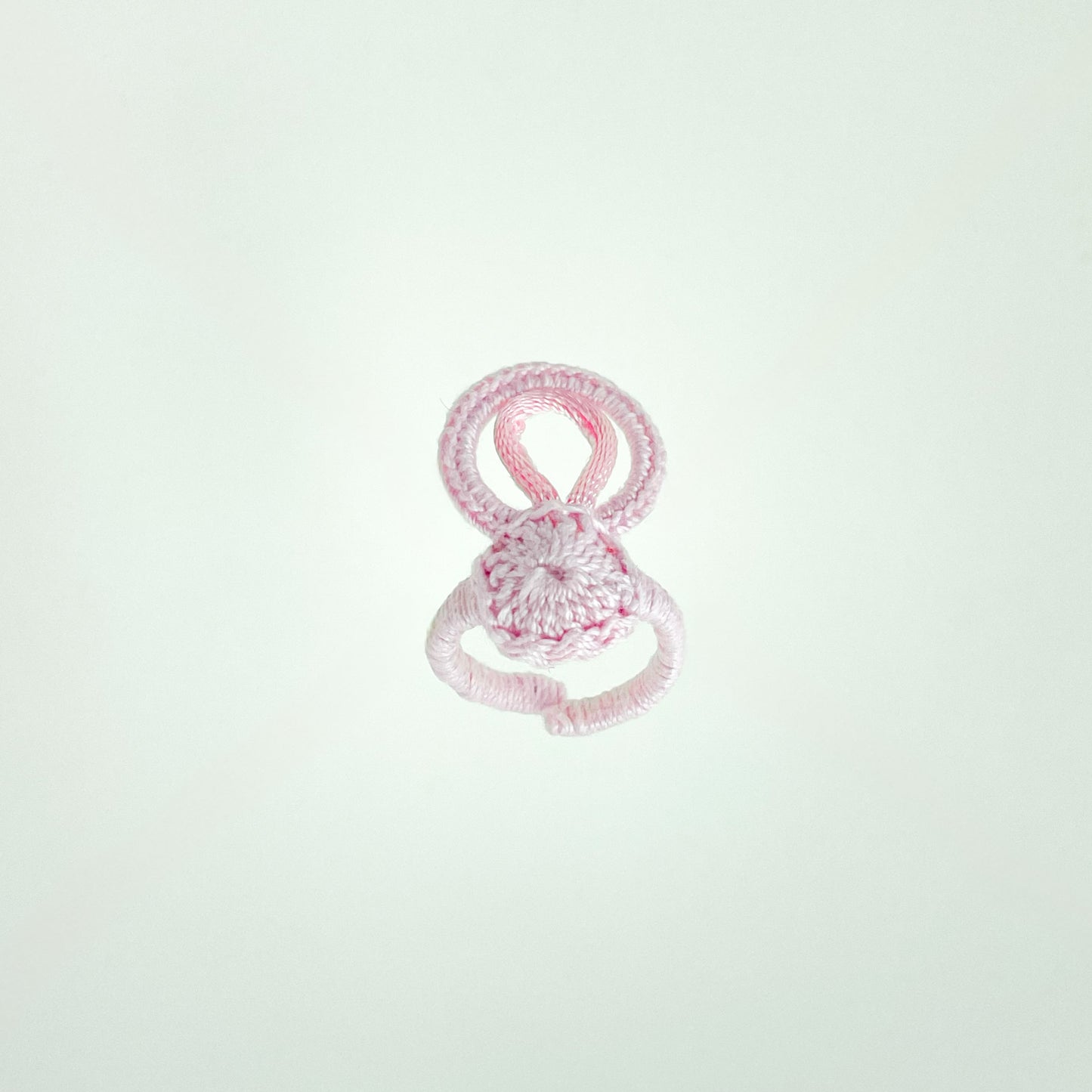 Blossom collection crochet ring in rose, photographed at a 45-degree angle to emphasize its soft curves and artisanal detail.