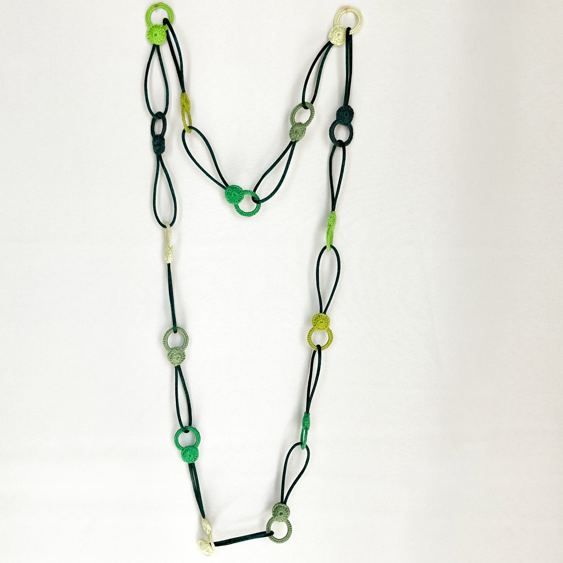 Versatile crochet necklace in flat lay showing flexible looped shape, adjustable design wearable as choker, lariat, or long necklace.