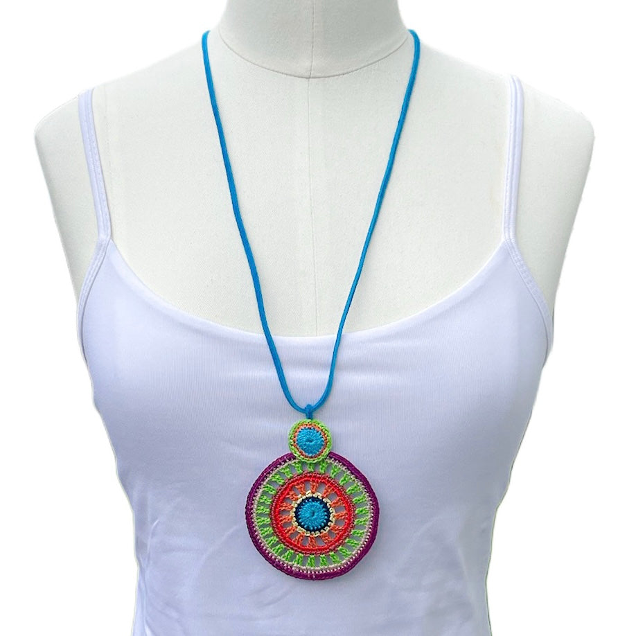 Handmade tropical crochet necklace in vibrant multicolored circles, worn long and loose for an elegant layered look — bold fiber statement jewelry by Crochet by Heart, shown on a mannequin with a white top.
