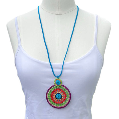 Handmade tropical crochet necklace in vibrant multicolored circles, worn long and loose for an elegant layered look — bold fiber statement jewelry by Crochet by Heart, shown on a mannequin with a white top.