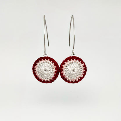 A pair of small round crochet earrings in currant and cloud colors with marquise ear wires.