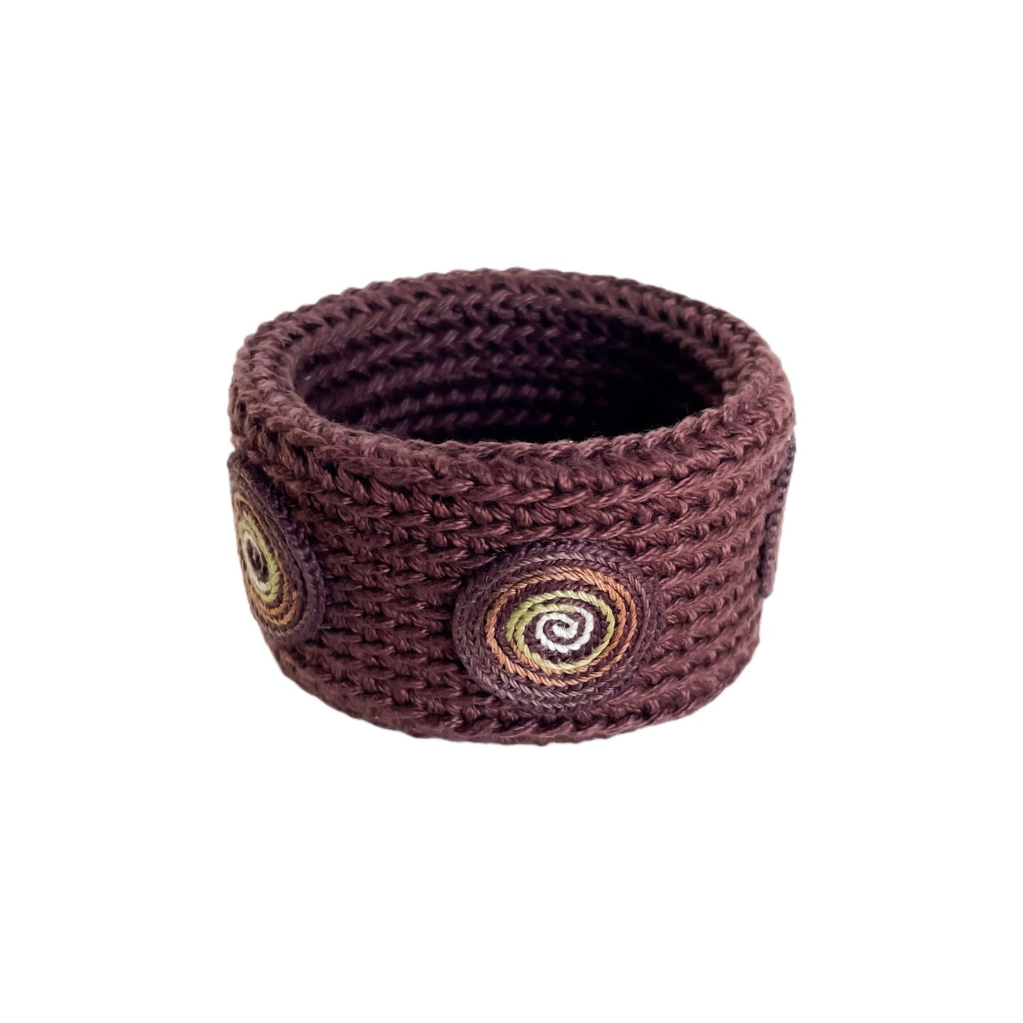 Brown Spiralis crochet bracelet with brown, green and ivory spiral design on a white background.
