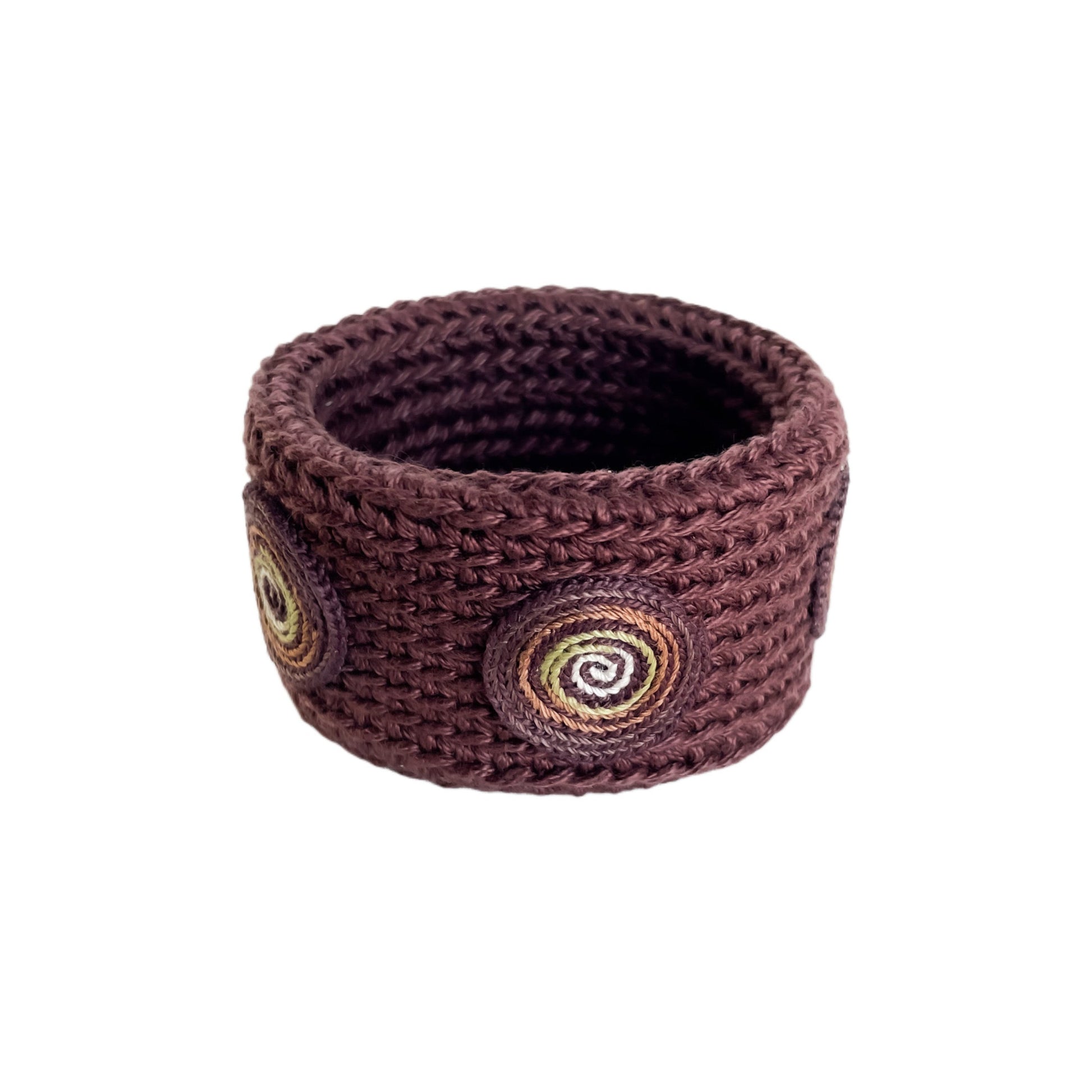 Brown Spiralis crochet bracelet with brown, green and ivory spiral design on a white background.