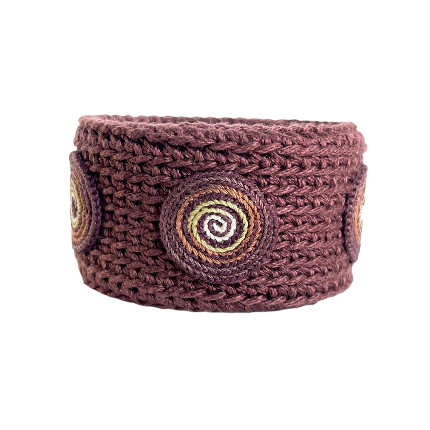 Brown Spiralis crochet bracelet with brown, green and ivory spiral design on a white background.
