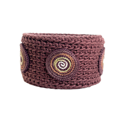 Brown Spiralis crochet bracelet with brown, green and ivory spiral design on a white background.