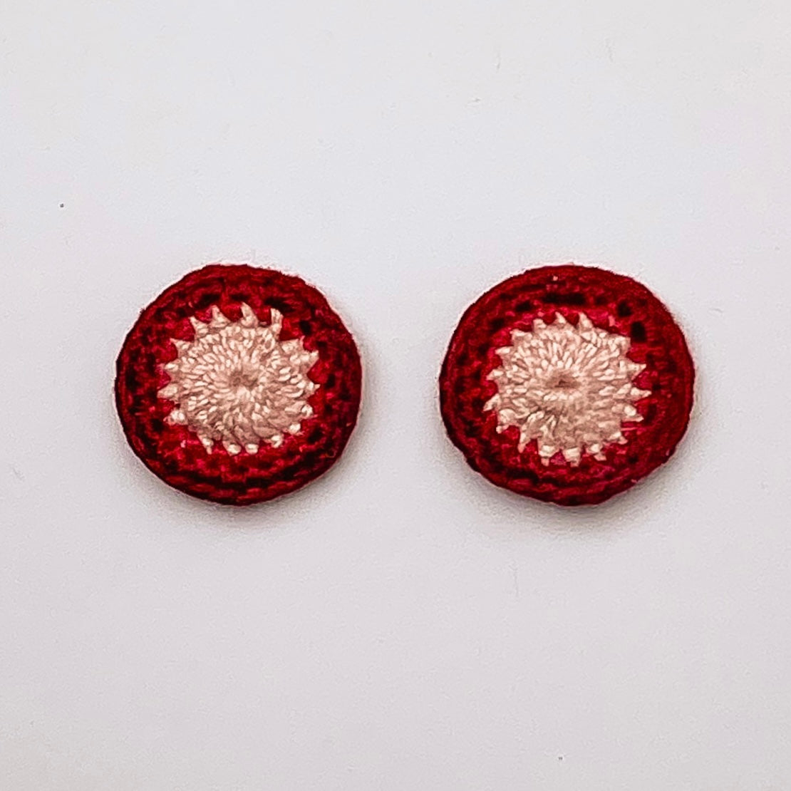 A close up of Kirk stud earrings. Small round earrings, colours: ivory, ruby and currant.