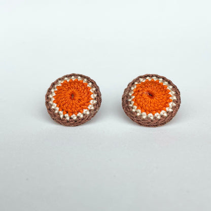 A close up of Kirk stud earrings. Small round earrings, colours: orange, ivory and chocolate. 