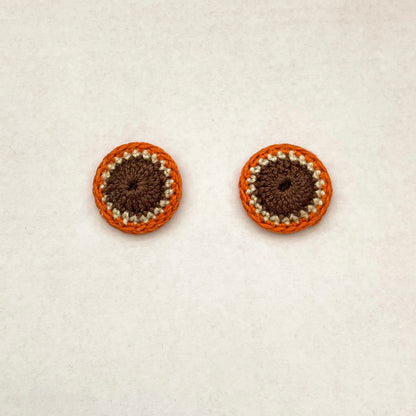 A close up of Kirk stud earrings. Small round earrings, colours: chocolate, ivory and orange.