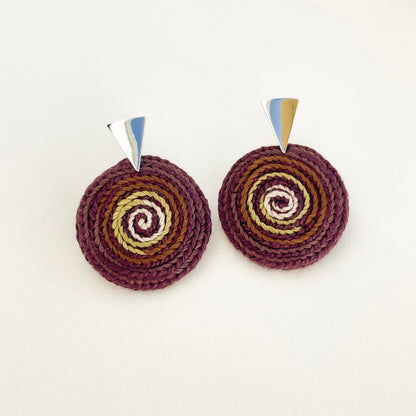 Handmade pair of round spiral crochet earrings in brown and green tones with metallic tops on a white background. 