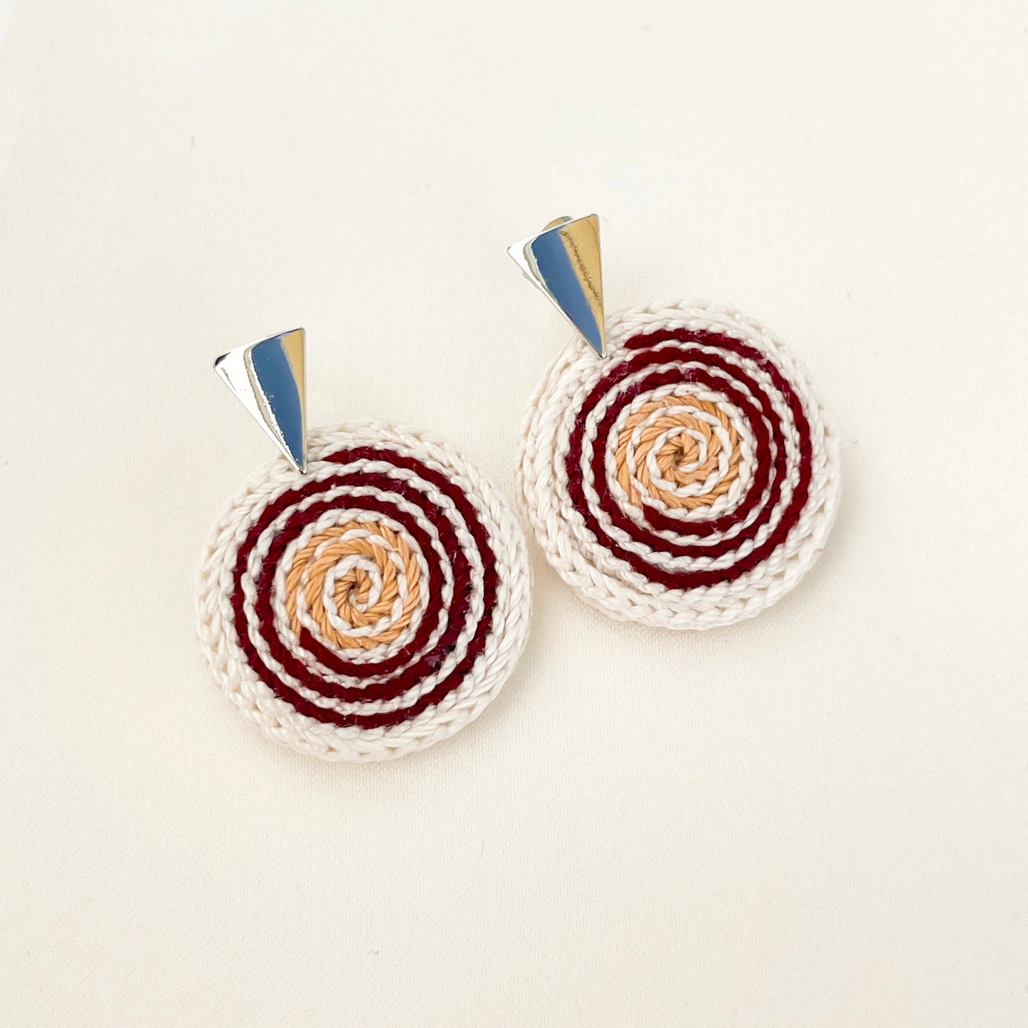 Spiralis Earrings in ivory, red and gold crochet with spiral pattern on a white background– handmade statement jewelry
