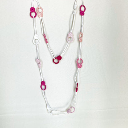 Versatile crochet necklace in pink tones flat lay showing flexible looped shape, adjustable design wearable as choker, lariat, or long necklace.