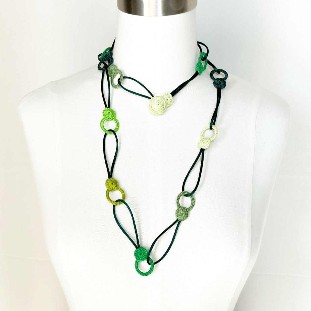 Green tones looped crochet necklace on mannequin with layering effect