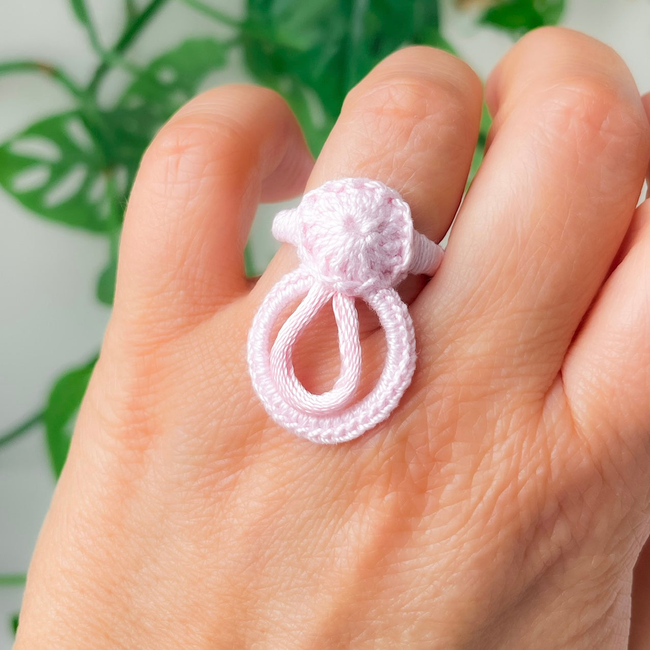 Rose handmade crochet ring with loop design photographed on hand.