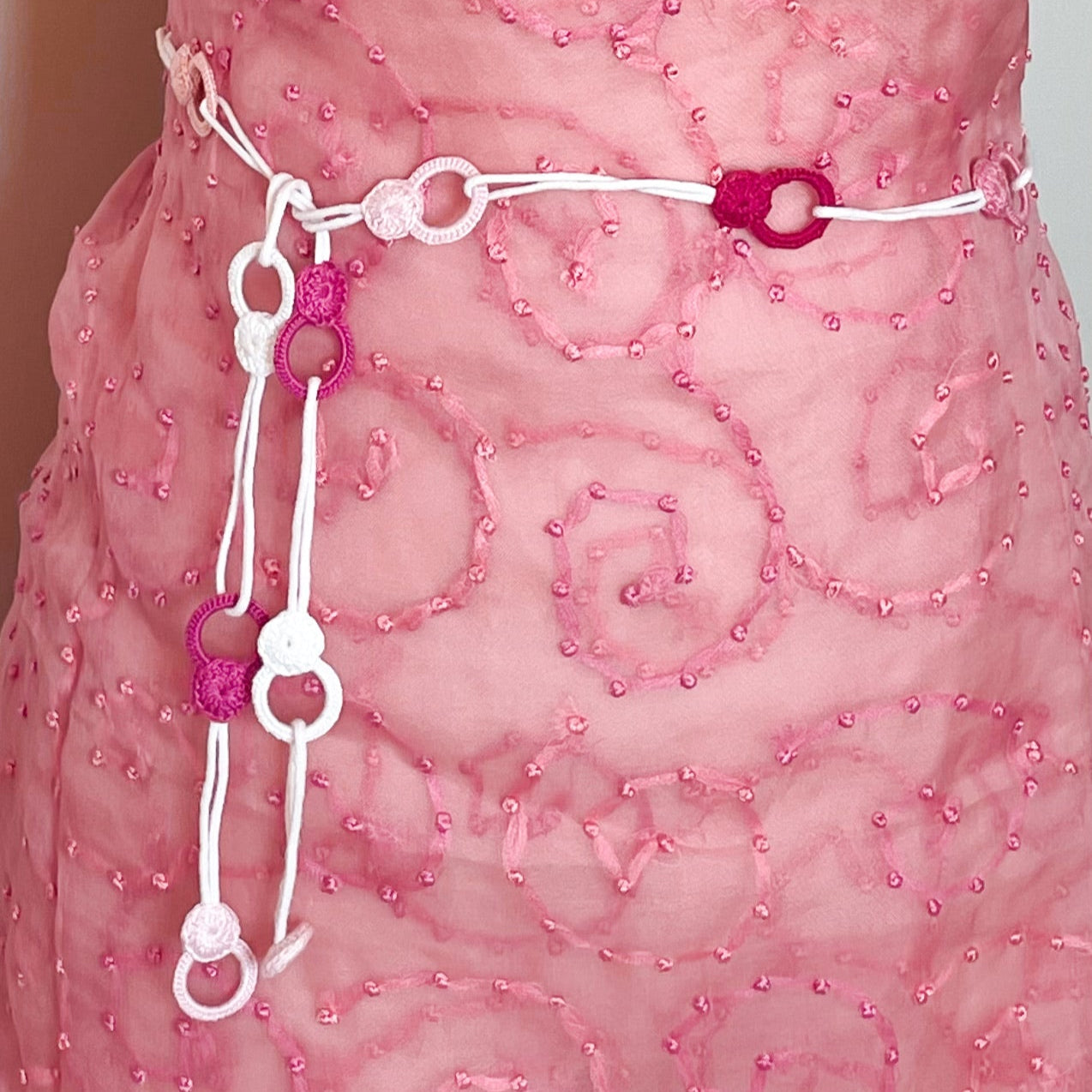 Handmade crochet necklace in pink tones worn as a belt, tied around the waist for a unique and modern accessory