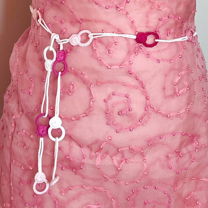 Handmade crochet necklace in pink tones worn as a belt, tied around the waist for a unique and modern accessory
