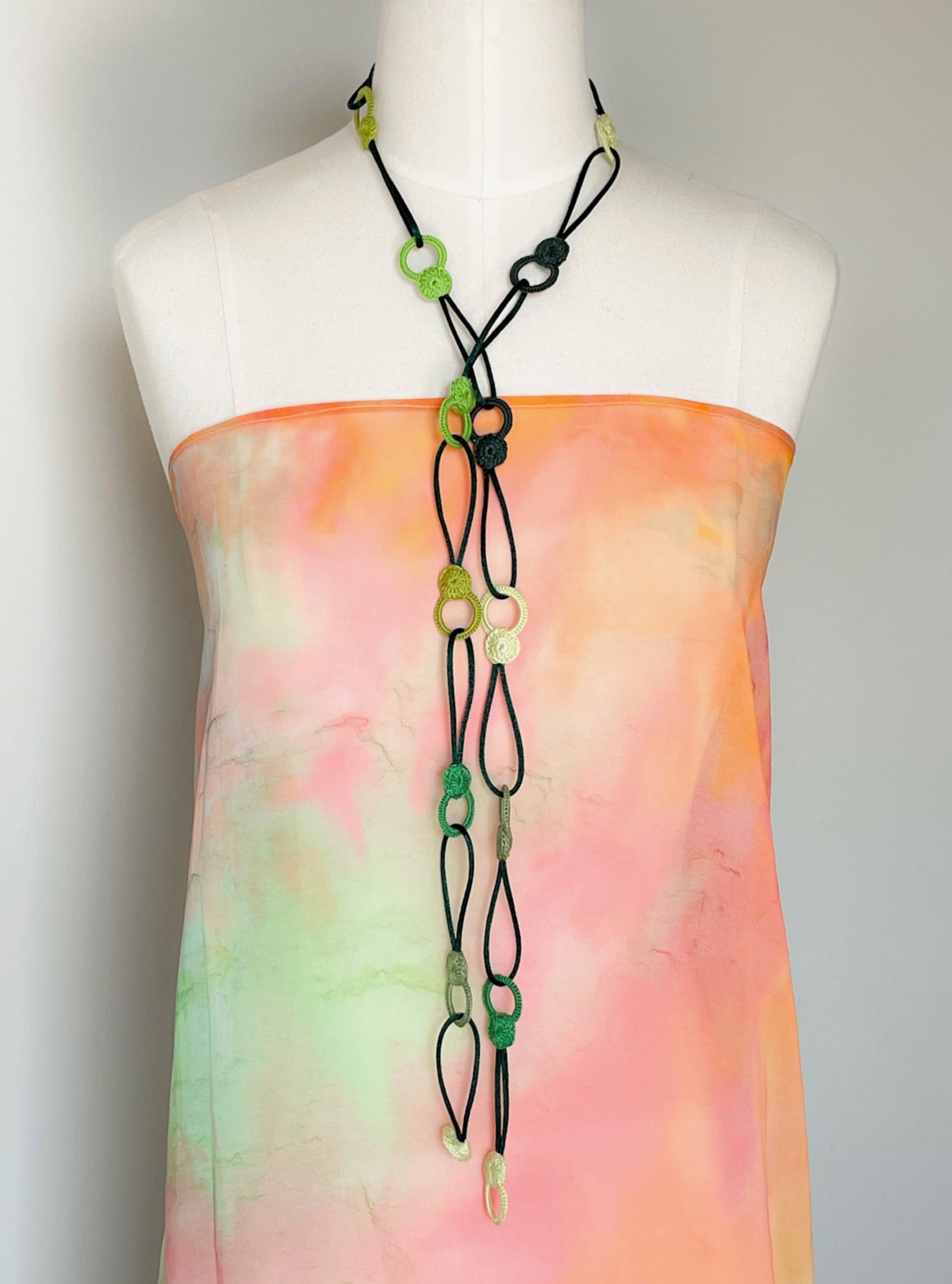 Convertible crochet necklace in green tones styled as a lariat with loose knot and long drop effect, artisan made in Chicago