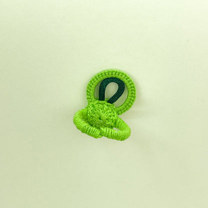 Rear view of the green crochet ring from the Blossom collection, displaying the fine crochet work and band construction