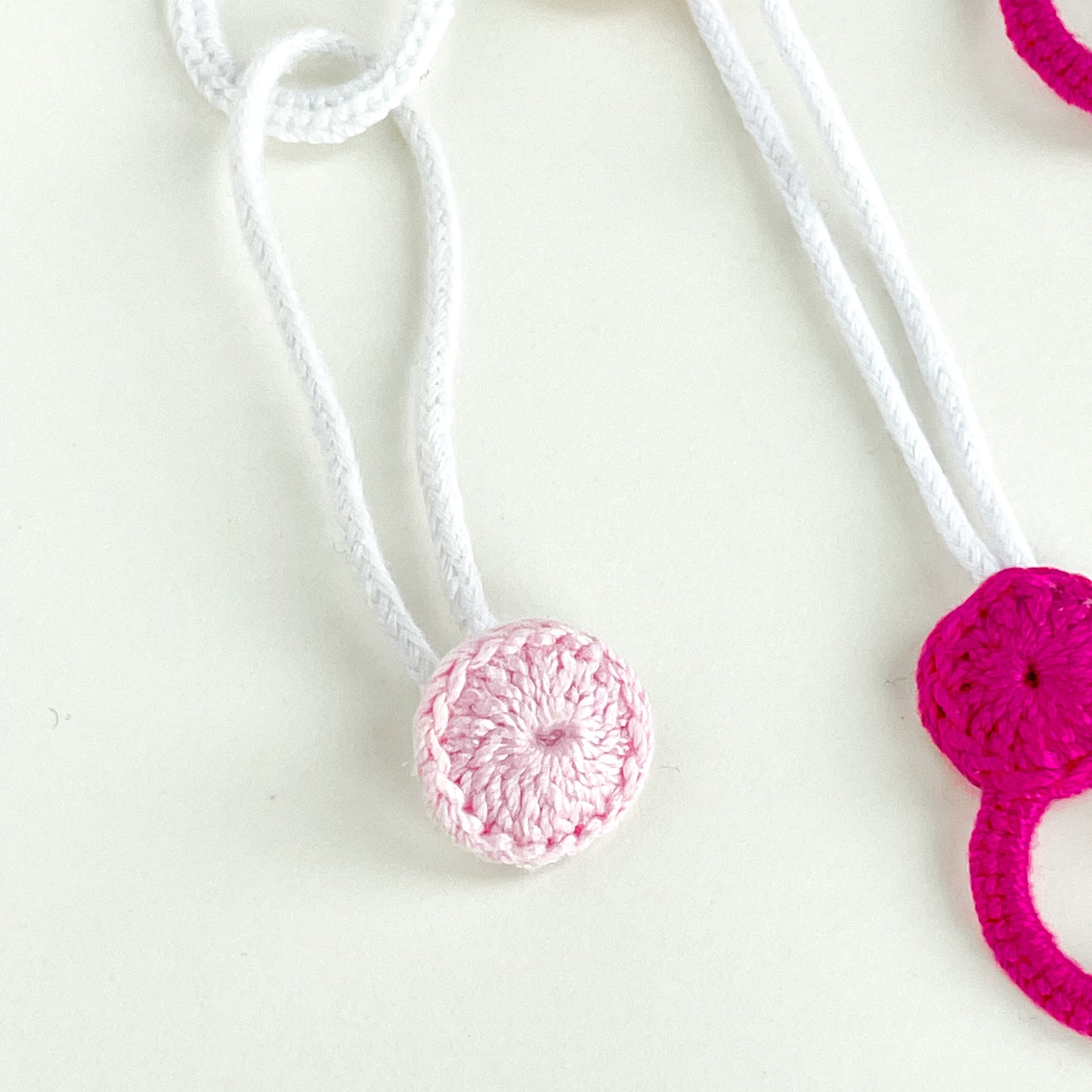 Close-up of the handmade crochet button from the Blossom collection, designed to slide into the loop and secure the necklace.