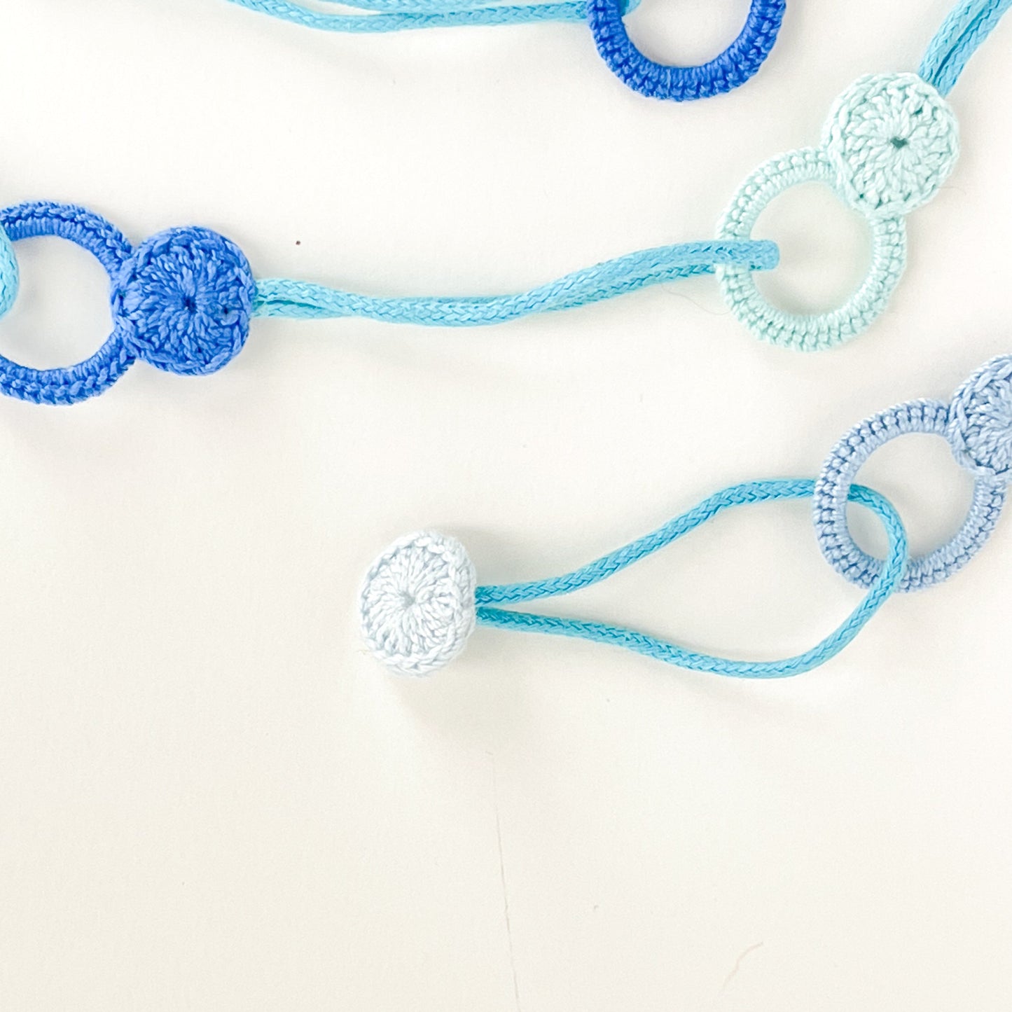Detail of the Blossom collection necklace clasp showing the crochet button that fits into the loop to close the necklace.