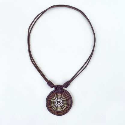 Necklace with a spiral pendant in brown and green tones with vegan suede adjustable straps on a white background.  