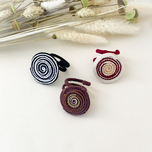 Three spiral-patterned rings on a white surface with dried plants in the background