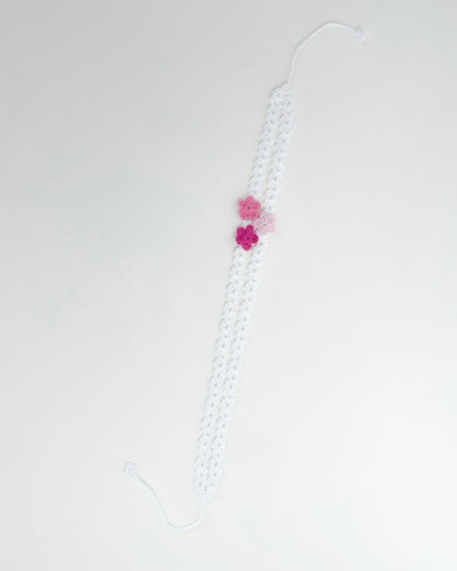 White crochet headband with three pink handmade crochet flowers on a delicate openwork band