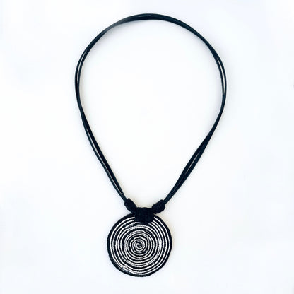 Necklace with a spiral pendant in black and white with vegan suede adjustable straps on a white background.  