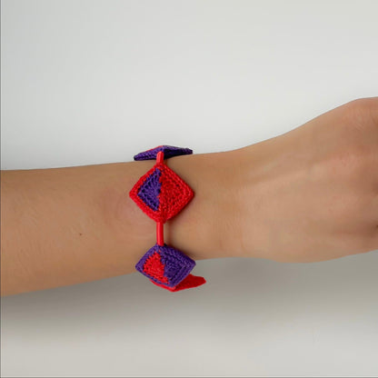 Hand wearing a red and blue bracelet on a white background