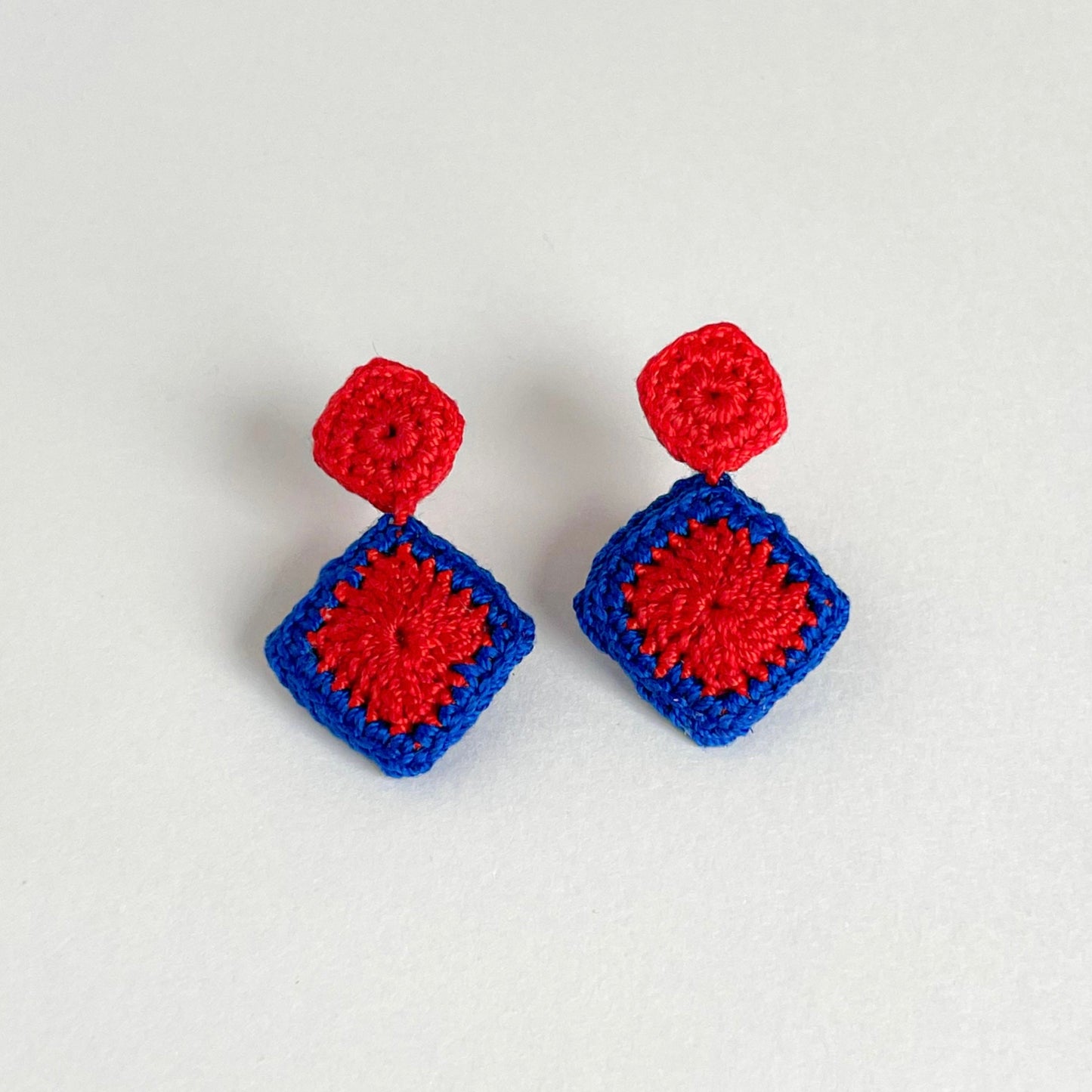 Pair of red and blue Tessera crochet earrings on a white background