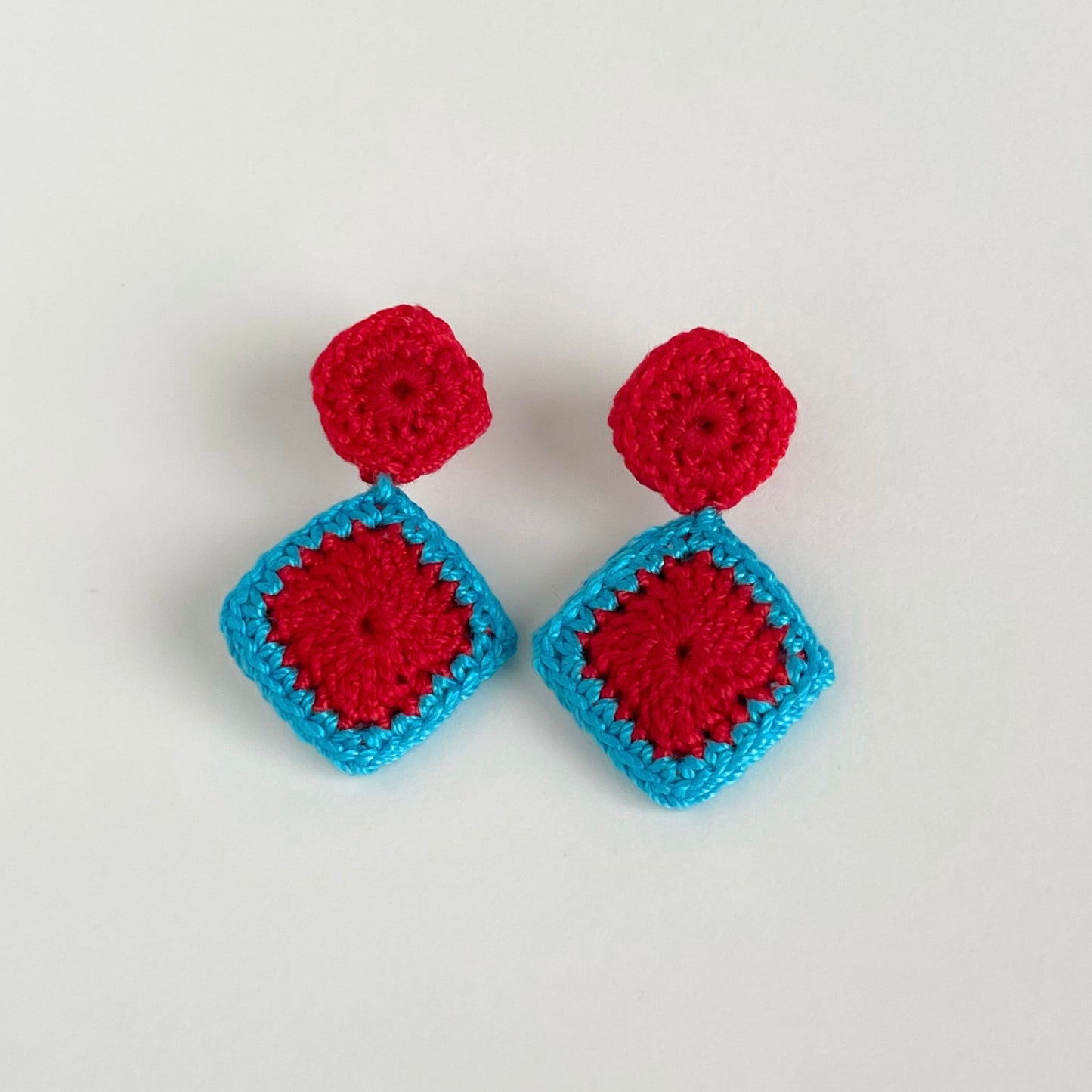 Pair of red and caribbean blue crochet earrings on a white background