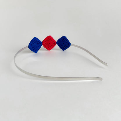 Back view of Tessera handmade crochet geometric headband with blue and red diamond motifs on silver metal band