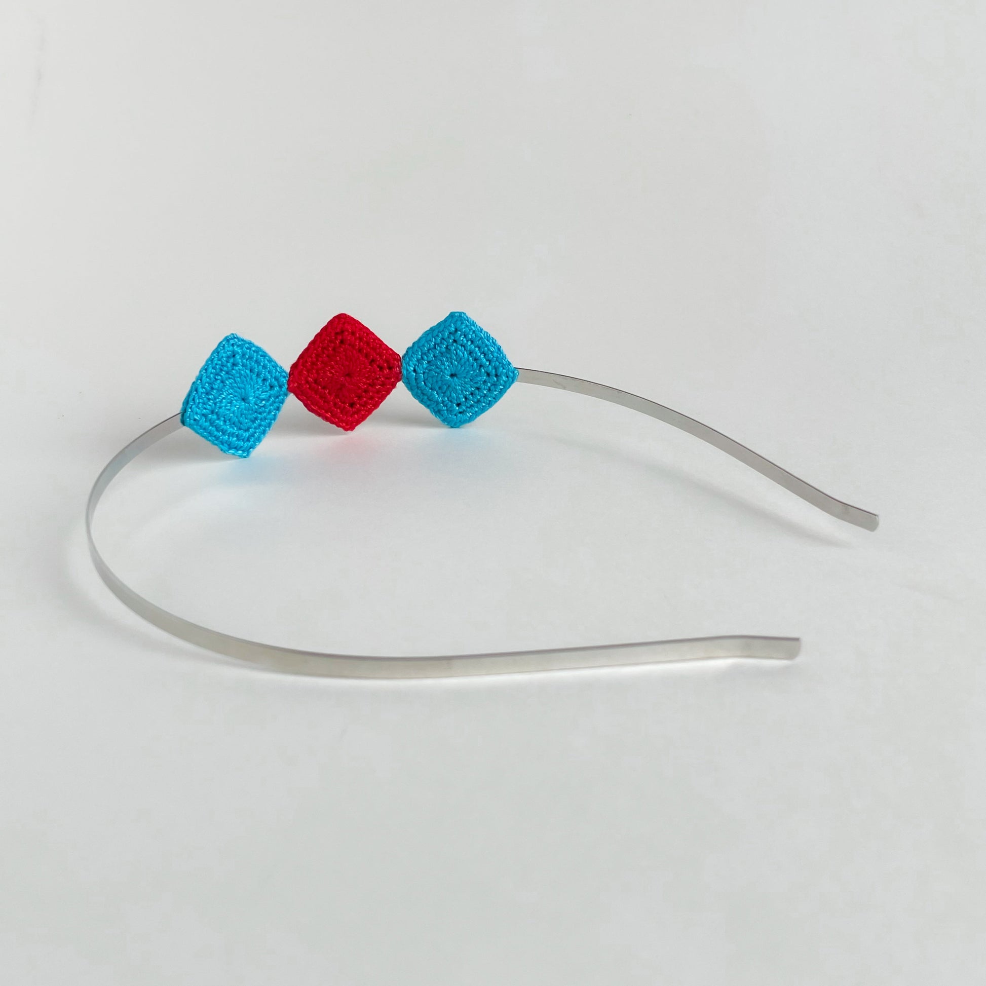 Back view of handmade crochet geometric headband with turquoise and red diamond motifs on silver metal band