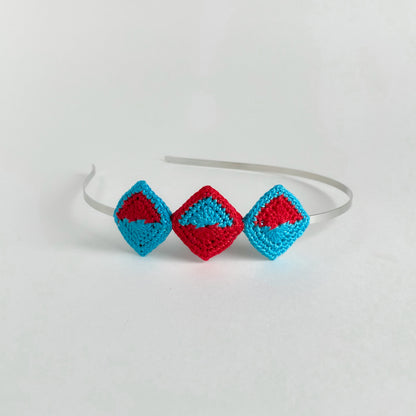 Handmade crochet geometric headband with diamond-shaped motifs in Caribbean blue (turquoise) and red mounted on metal band