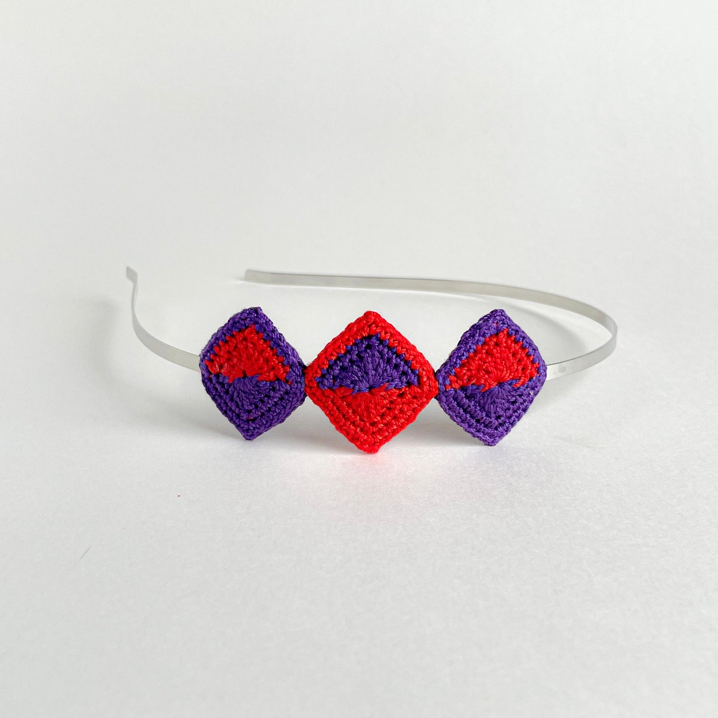 Tessera handmade crochet geometric headband with diamond-shaped motifs in violet and red mounted on metal band