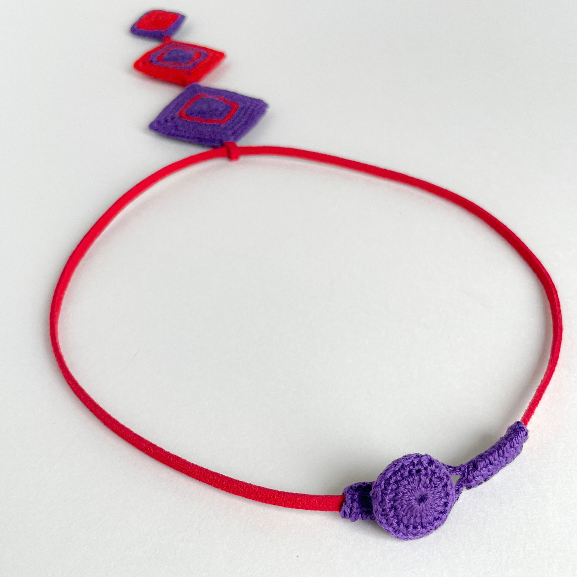 Crocheted necklace with a purple clasp on a white background