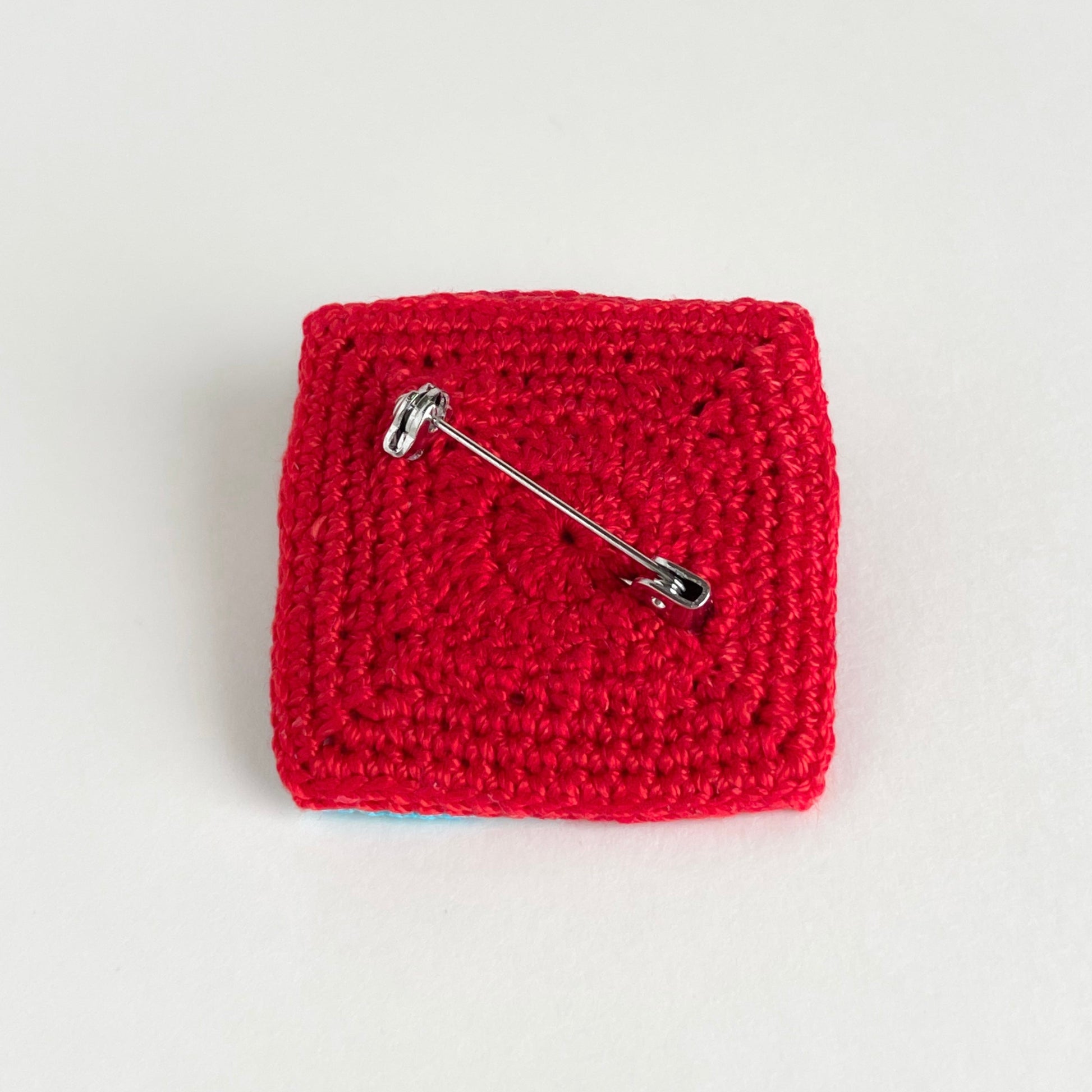 Back view of the Tessera Pin in red on a white background by Crochet by Heart.