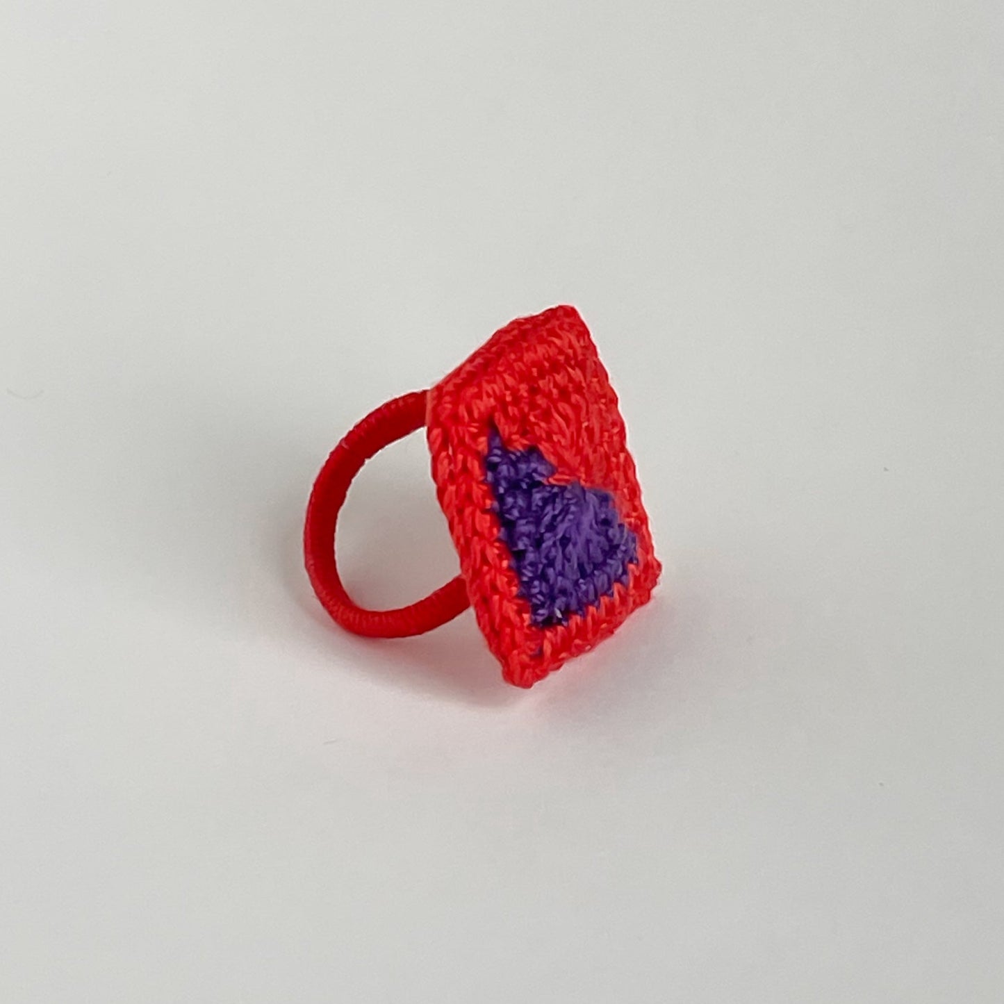 Red and violet crocheted ring on a light gray background