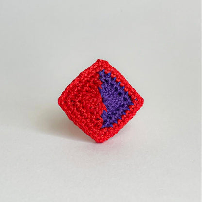 Front view of the Tessera geometric crochet ring by Crochet by Heart with alternating red and violet geometric details.
