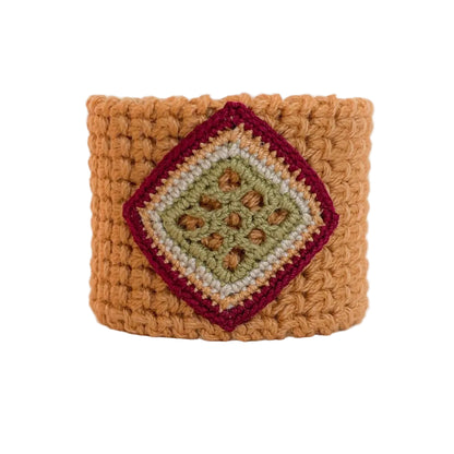 Front view of the TRAMA marigold crochet cuff bracelet with a moss green openwork motif bordered in bege, gold, and burgundy.