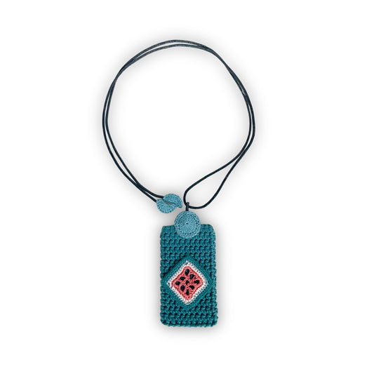 TRAMA crochet necklace with a teal rectangular pendant, a clay, cream and blue jade diamond motif, and a black cord on a white background.