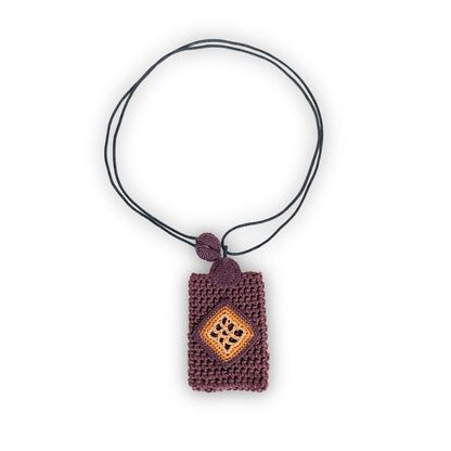 TRAMA crochet necklace with a brown rectangular pendant, a chocolate, ginger and marigold diamond motif, and a black cord on a white background.