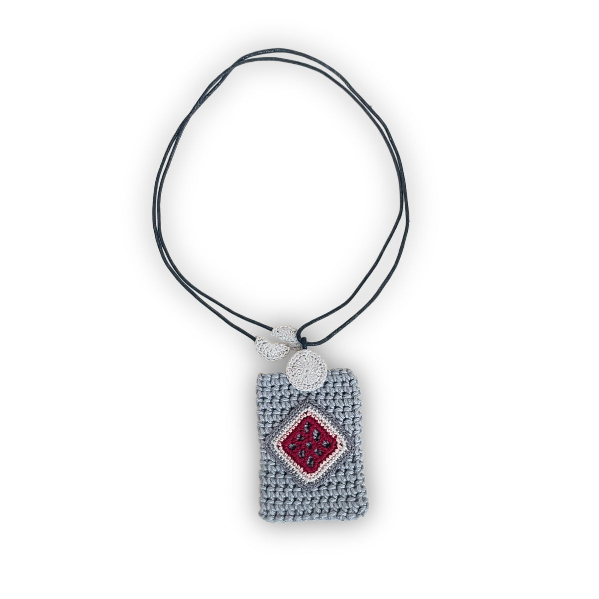 TRAMA crochet necklace with a gray rectangular pendant, an rose, cream and burgundy diamond motif, and a black cord on a white background.