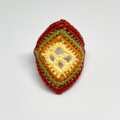 TRAMA cooper crochet ring with an elongated diamond shape, yellow butter openwork centre and moss green border on a white background.